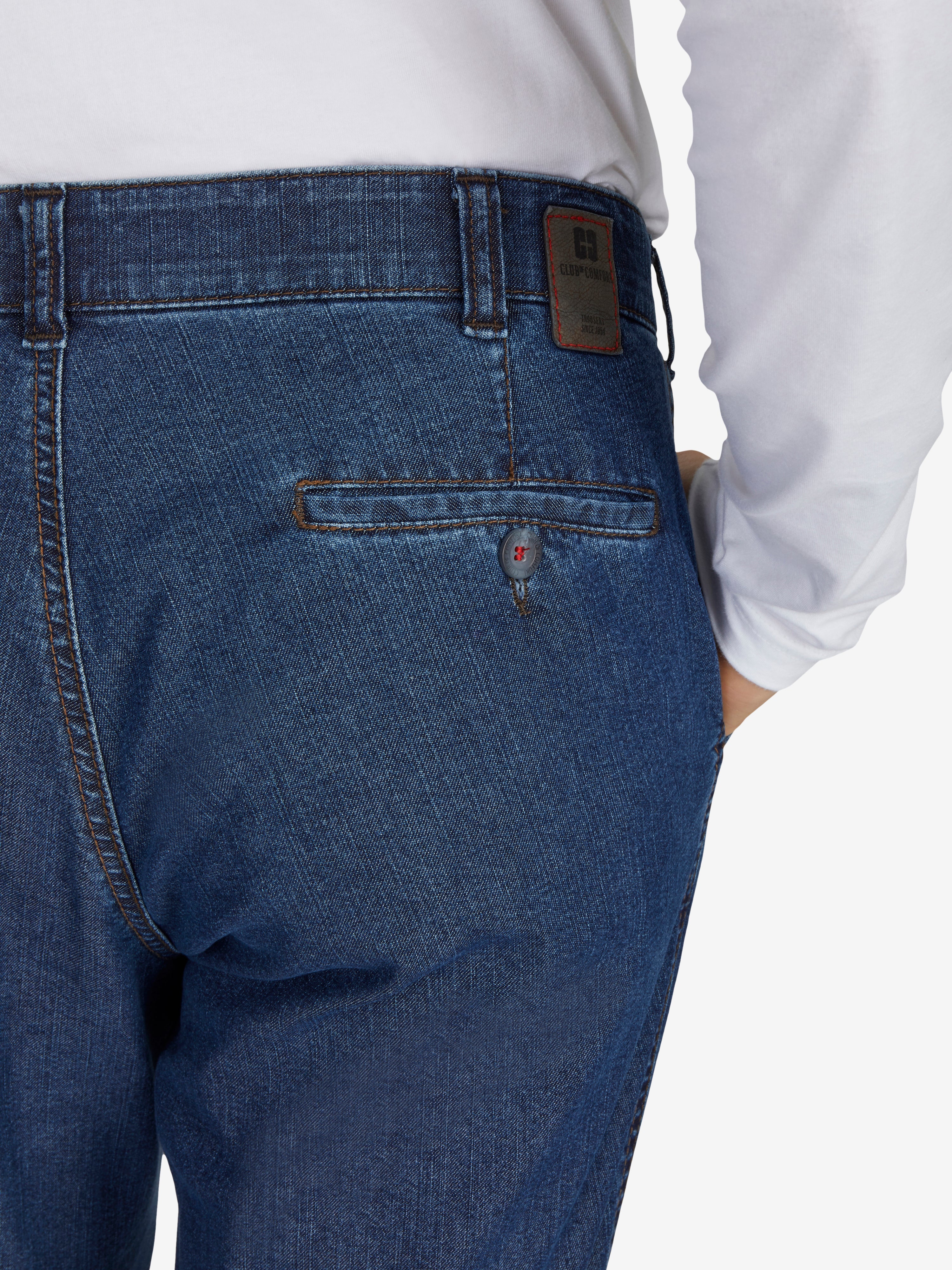 Nahaufnahme einer Jeansblauen DALLAS 4631 Hose von Club of Comfort mit elastischem Komfortbund, Hemdenstopper, geradem Bein, aus robustem Stretch-Ring-Denim, getragen von einer Person in Weißem Oberteil.