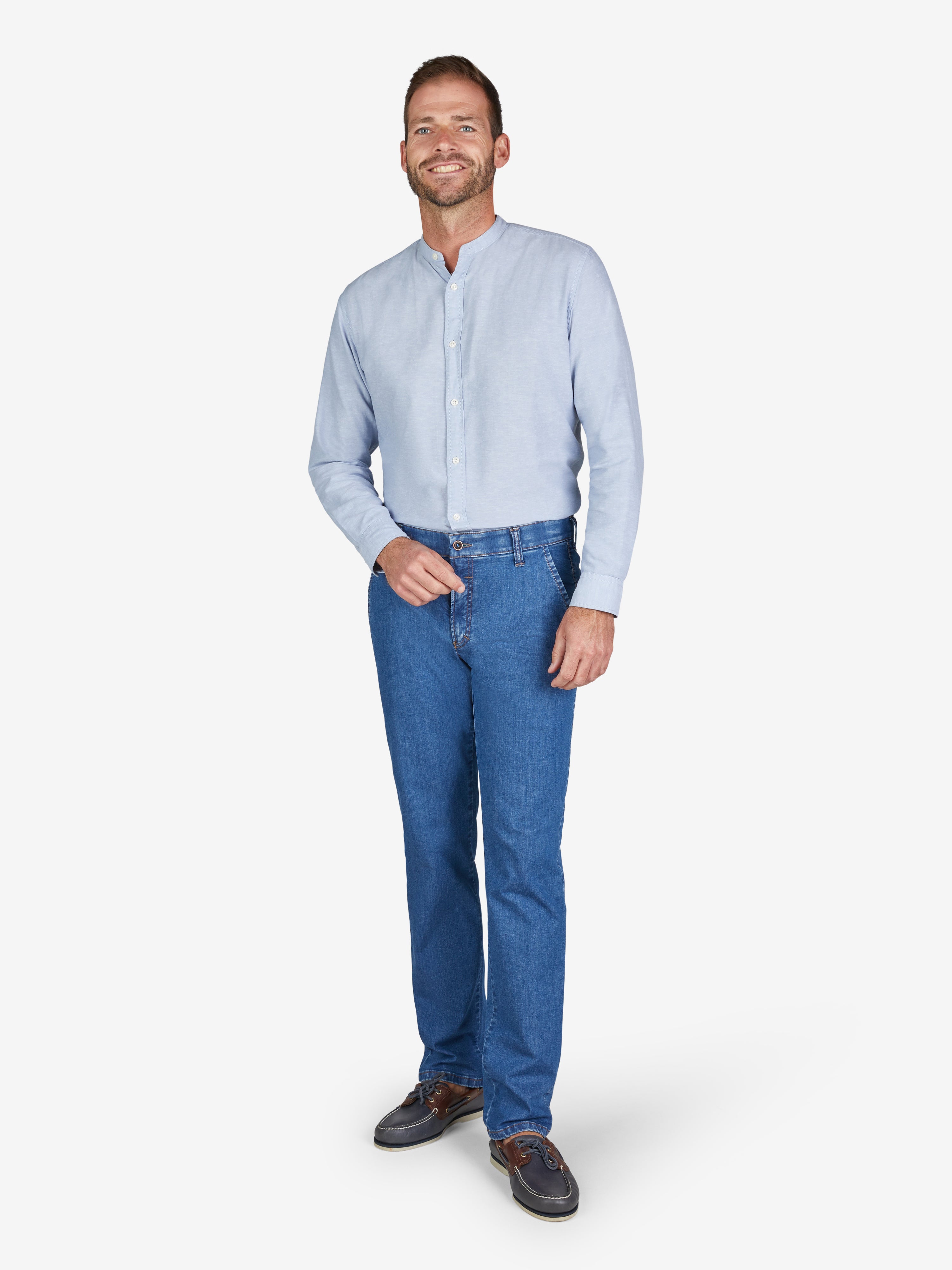 Mann trägt eine hellblaue, lange Hemd-Stopper-Knopfleinen. Dazu eine jeansblaue GARVEY 6516 Flat Front-Hose mit elastischem Komfortbund, hoher Elastizität durch Lycra dual-FX®-Technologie, Regular Fit und schmalerer Fußweite. Hosenmodell für Frühjahr/Sommer, hergestellt aus leichtem, hoch elastischem Super High Stretch-Denim.