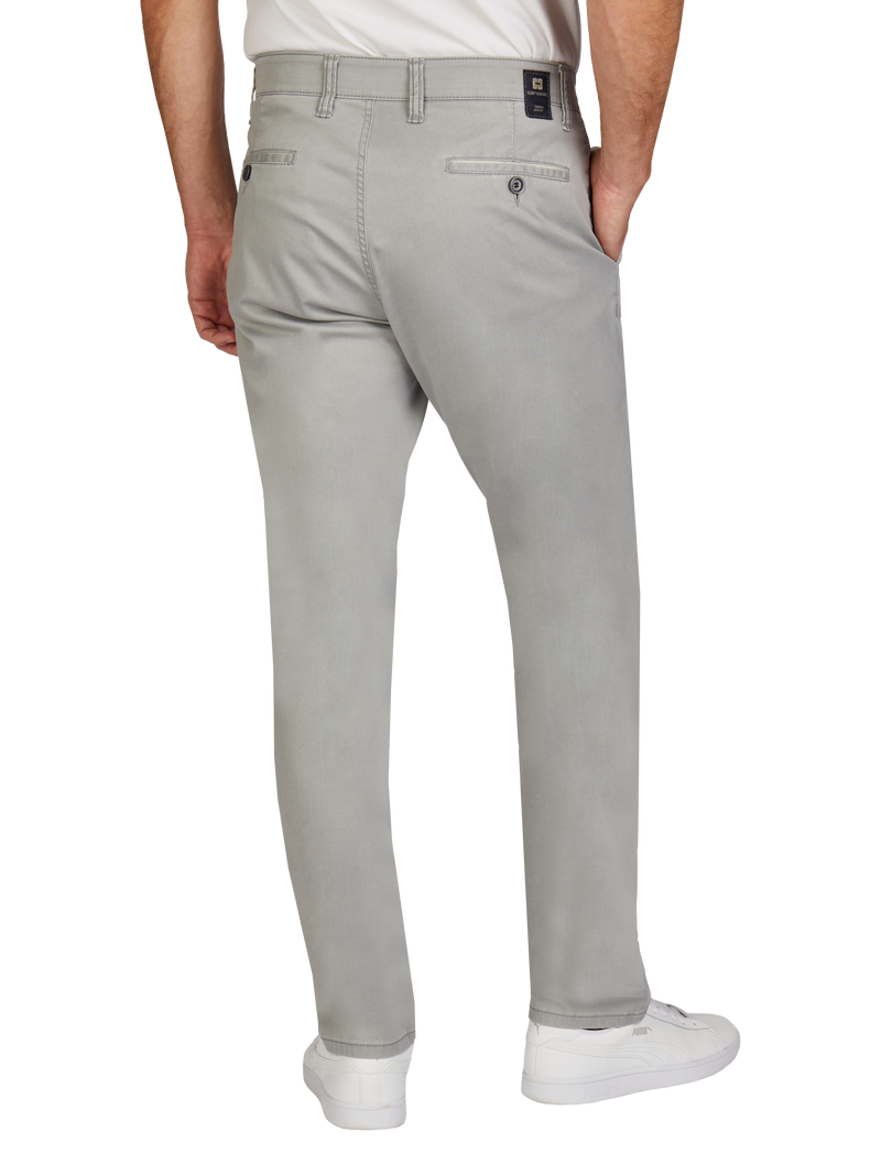 Hier sind die Hüften und Beine eines Mannes, der hellgraue Jeans trägt. Er steht mit den Händen in den Taschen, trägt weiße sneakers und ein weißes T-Shirt.