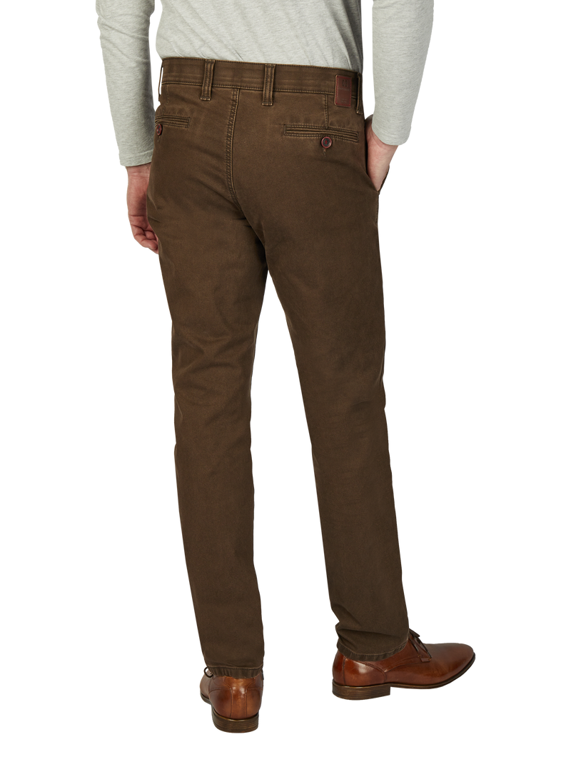 Hintere Ansicht eines Mannes, der braune Chino-Hose trägt, mit einer Hand in der Hosentasche. Er trägt eine graue, lange Ärmeloberseite und braune Lederschuhe.