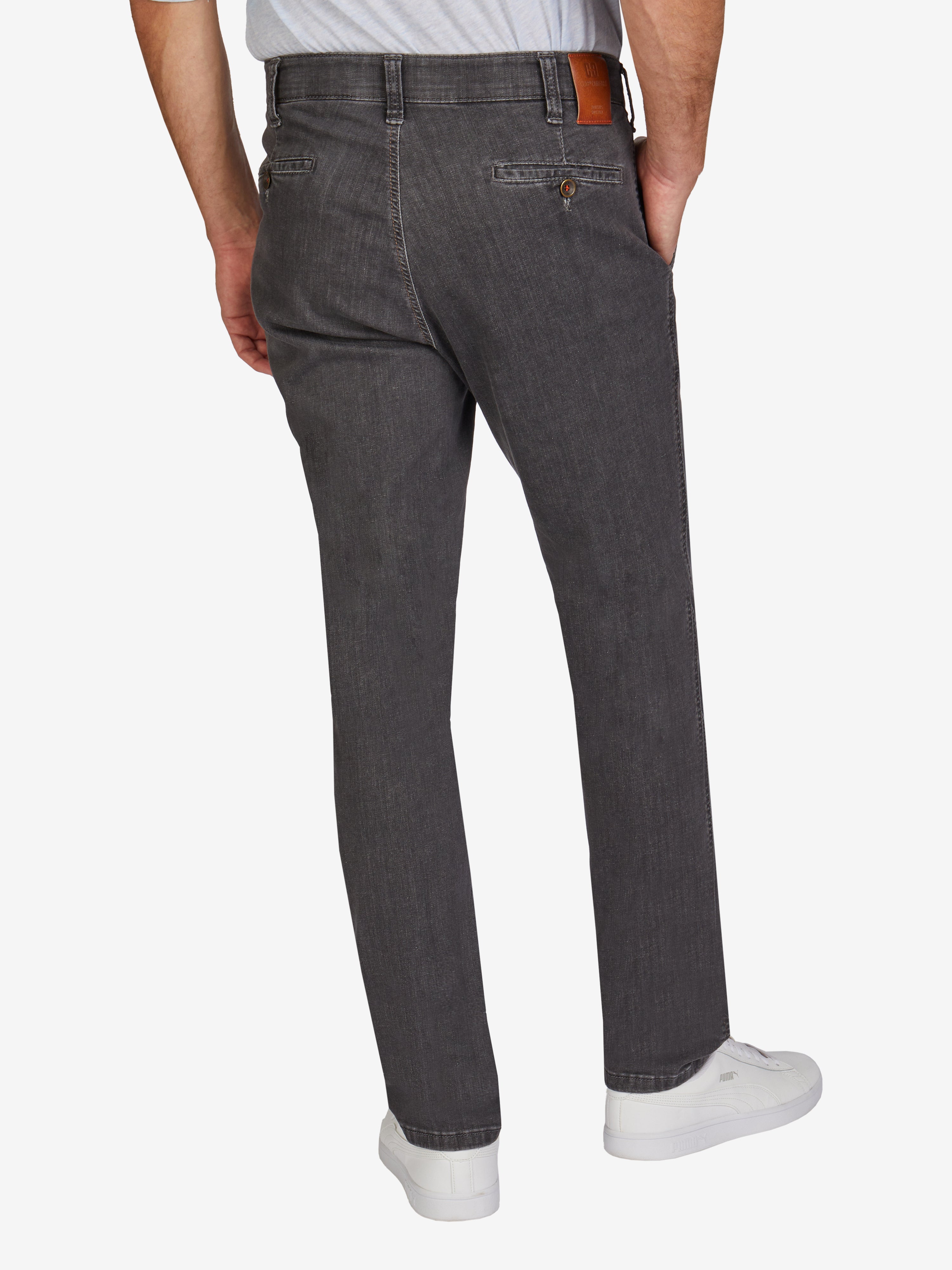 Graue GARVEY 7915 Flat Front-Hose aus hoch elastischem Super High Stretch-Denim mit elastischem Komfortbund, Hemdstopper, Bundverlängerung mit Knopf und Haken, normaler Leibhöhe, schmaler Fußweite, Regular Fit, made in Green by Oeko-Tex, für ganzjährige Nutzung, modelliert von hinten, getragen mit weißem T-Shirt und Sneaker.