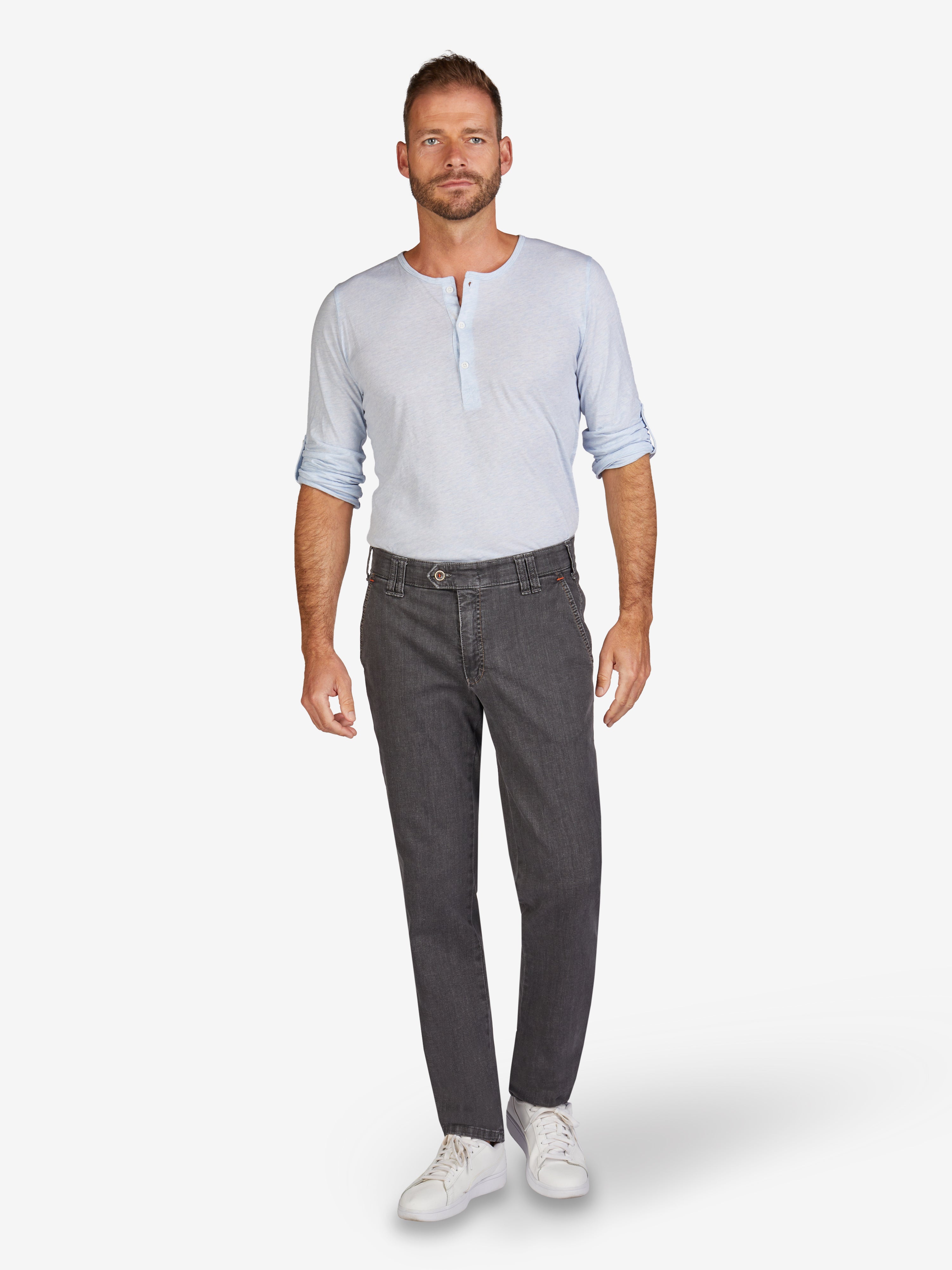 Mann trägt eine hellblaue, langärmlige Flat Front-Hose GARVEY 7915 in Anthrazit mit elastischem Komfortbund, Hemdstopper und Bundverlängerung mit Knopf und Haken. Hoch elastischer Super High Stretch-Denim mit Lycra dual-FX®-Technologie, normale Leibhöhe, schmaler Beinverlauf.