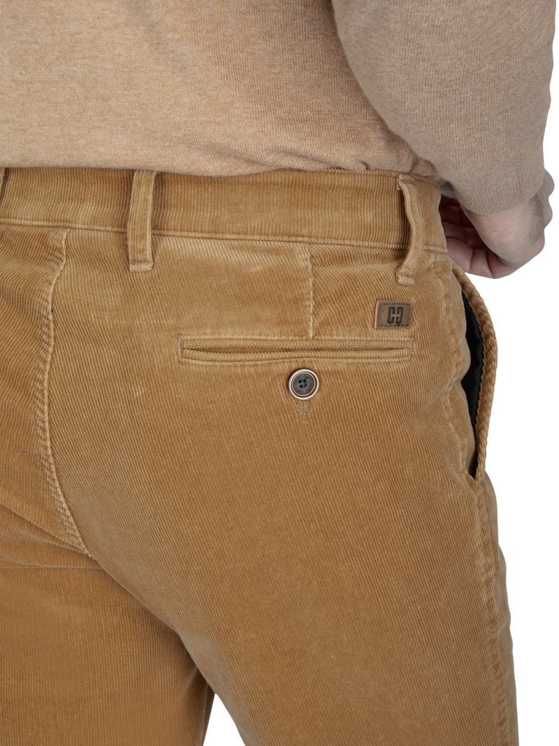 Nahaufnahme der unteren Rückenpartie einer Person, die hellbraune Cordhosen trägt. Die Hose hat eine hintere Eingrifftasche mit Knopf und einen kleinen Leder-Label. Die Person trägt ein beige Oberteil.