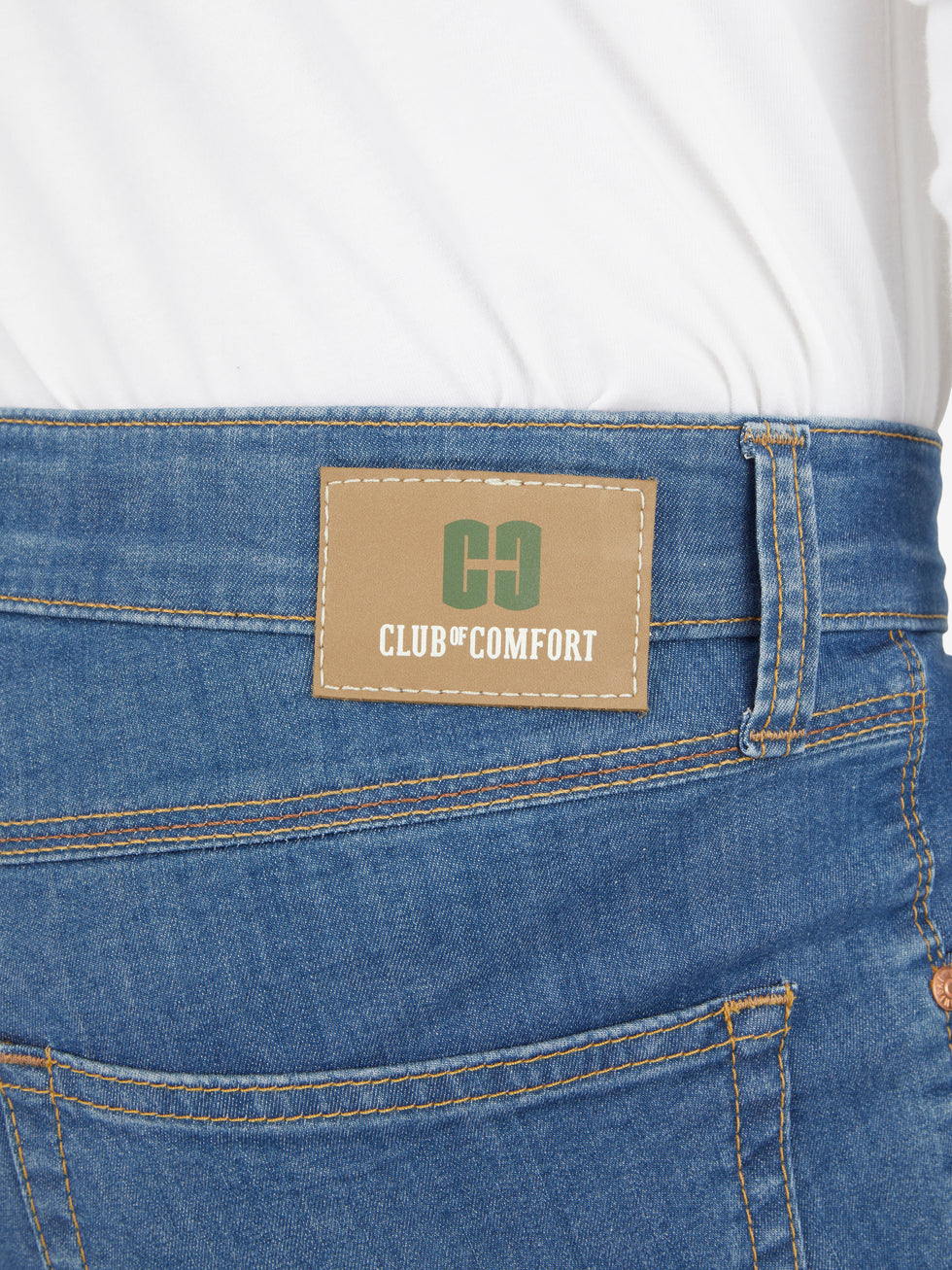 Nahaufnahme der blauen 5-Pocket-Jeans von Club of Comfort mit elastischem Doppelstoffbund, Mobile Pocket in der rechten Vordertasche, Münztasche mit Kontrast-Patch, hergestellt aus hoch elastischem Super High Stretch-Denim, mit Label auf der Hüfte.