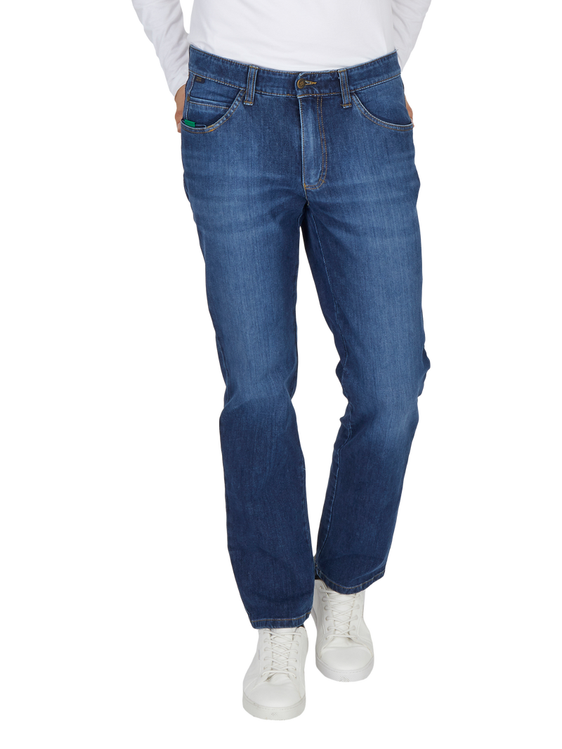 Hüfthose in blauer Denim-Jeans mit geradem Schnitt, eingelassenen Taschen vorne, einen aus der linken Backentasche herausragenden kleinen Gegenstand, weiße Sneakers und ein weißes Oberteil.