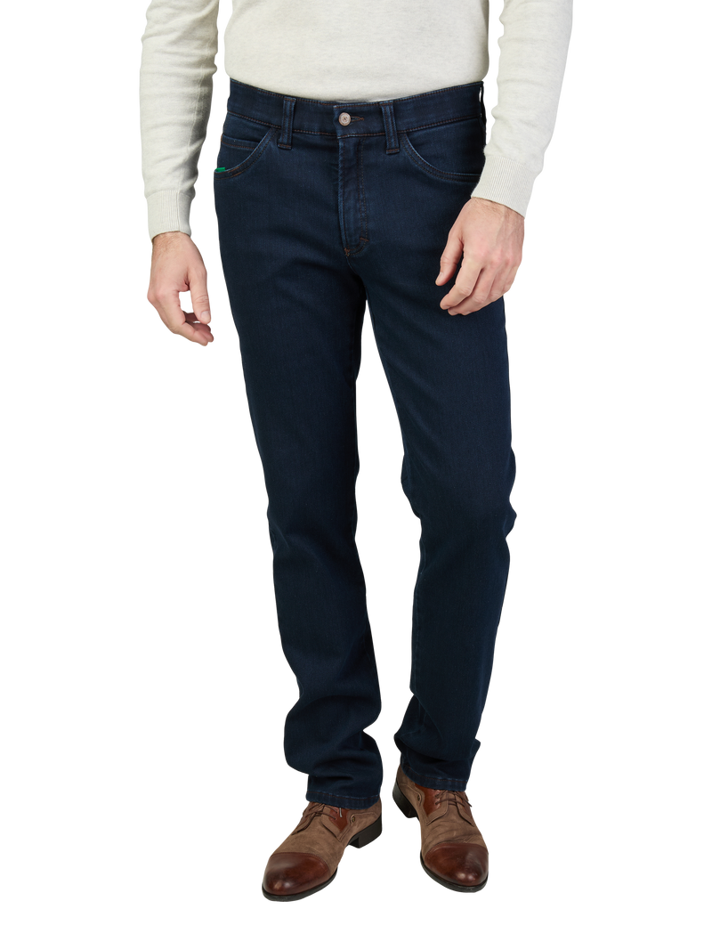 Ein Mann trägt dunkelblaue Denim-Jeans, eine beige Pullover und braune Lederstiefel.