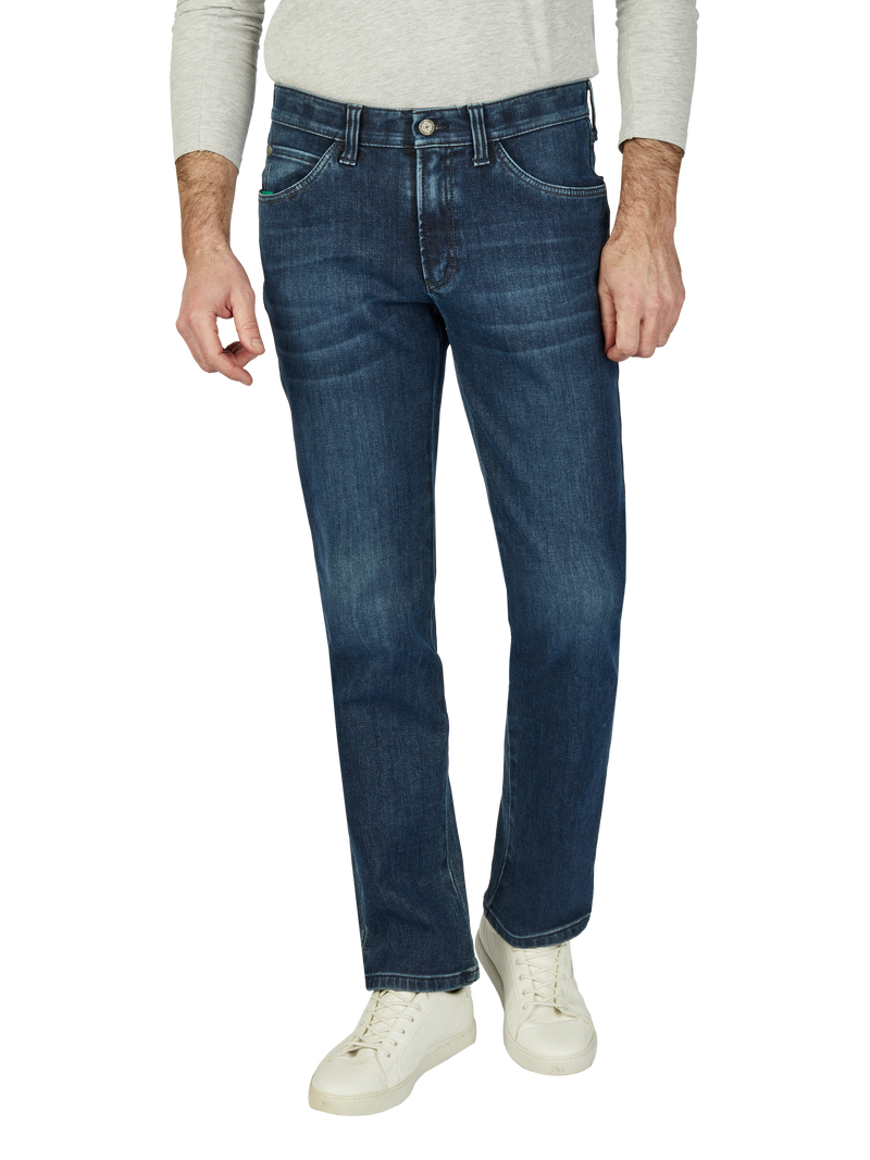 Blick auf einen Mann in blauen Jeans, einem hellgrauen Pullover und weißen Sneakers, nur der Oberkörper bis zu den Knien ist sichtbar.