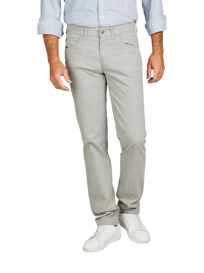 Mann trägt hellgraue, gerade geschnittene Jeans, ein hellblaues Hemd mit aufgekrempelten Ärmeln und weiße Sneakers. Das Bild zeigt den unteren Teil des Körpers, ohne Kopf.