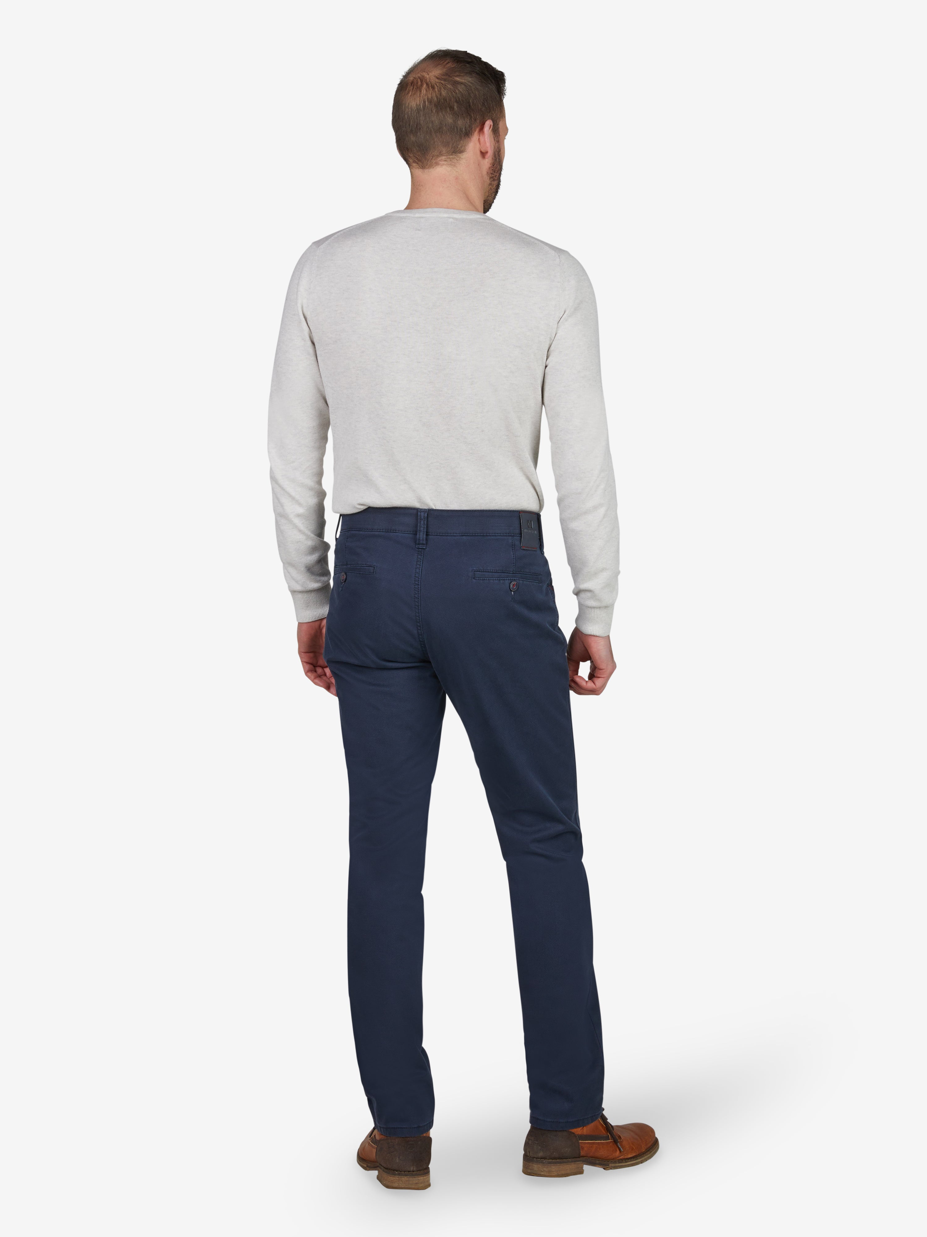 Ein Mann steht mit gedrehter Rückenansicht in einer blauen Marine-Hose von Club of Comfort, Modell MARVIN 8225. Die Hose ist eine modifizierte 5-Pocket-Jeans mit Regular Fit, Komfortbund, elastischem High Stretch-Baumwollgewebe mit Thermolite-Wärmeisolierung, ideal für Herbst/Winter.