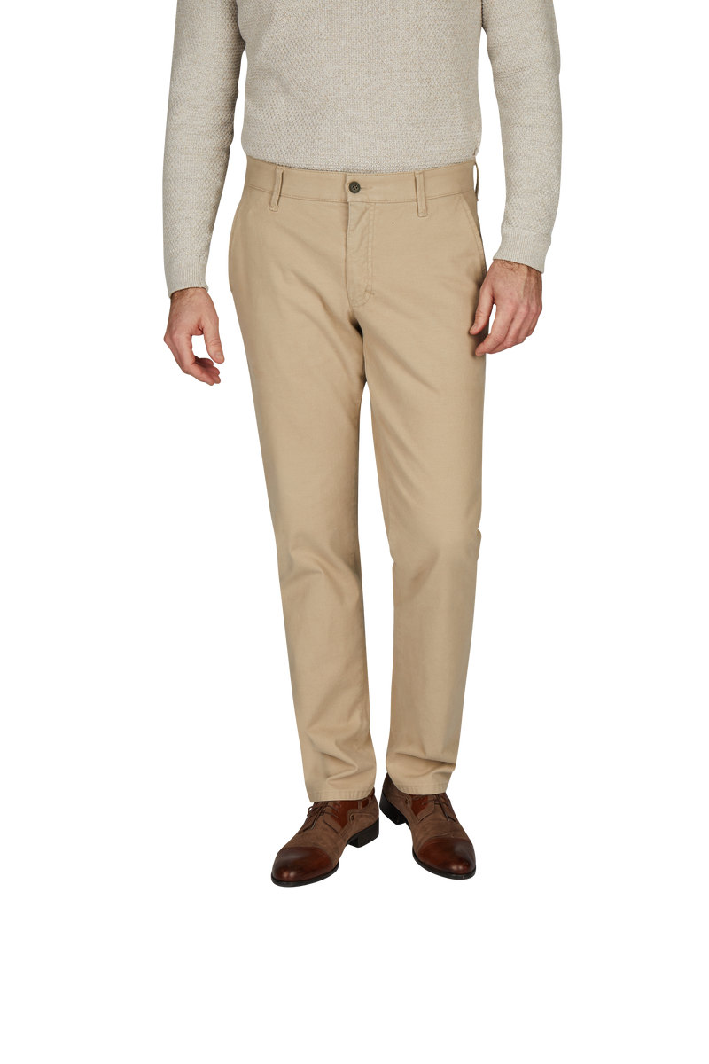 Bäuchlingssicht auf einen Mann, der beige Chino-Hosen, braune Lederschuhe und ein hellgraues Oberteil trägt. Der Kopf ist nicht sichtbar.