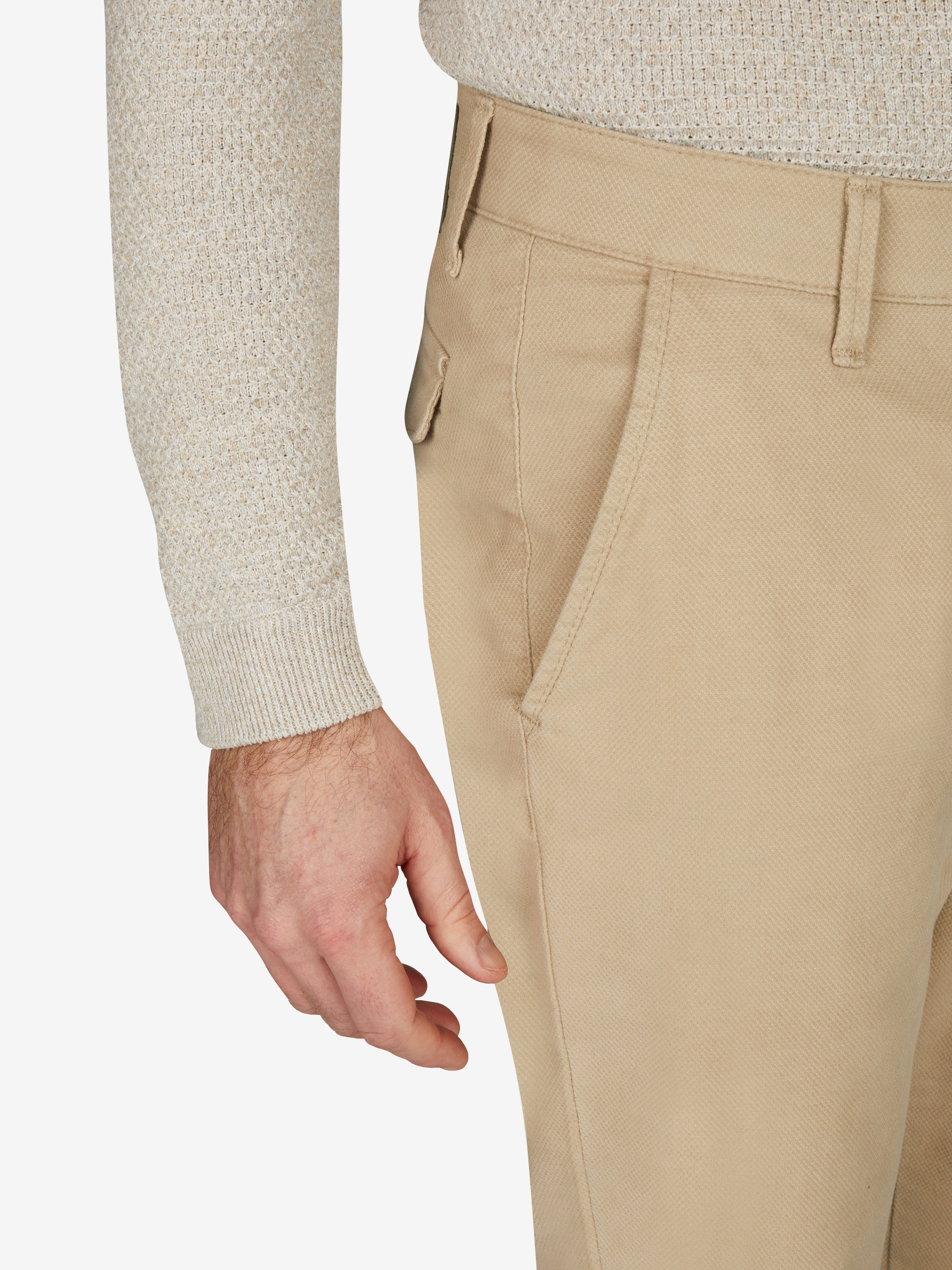 Nahaufnahme einer beigefarbenen Chino-Hose des Modells ROB 8003 im Tapered Fit von Club of Comfort, mit elastischem Comfortbund, Hemdenstopper und hoher Stretch-Baumwollstruktur, getragen von einer Person mit heller Strickjacke.