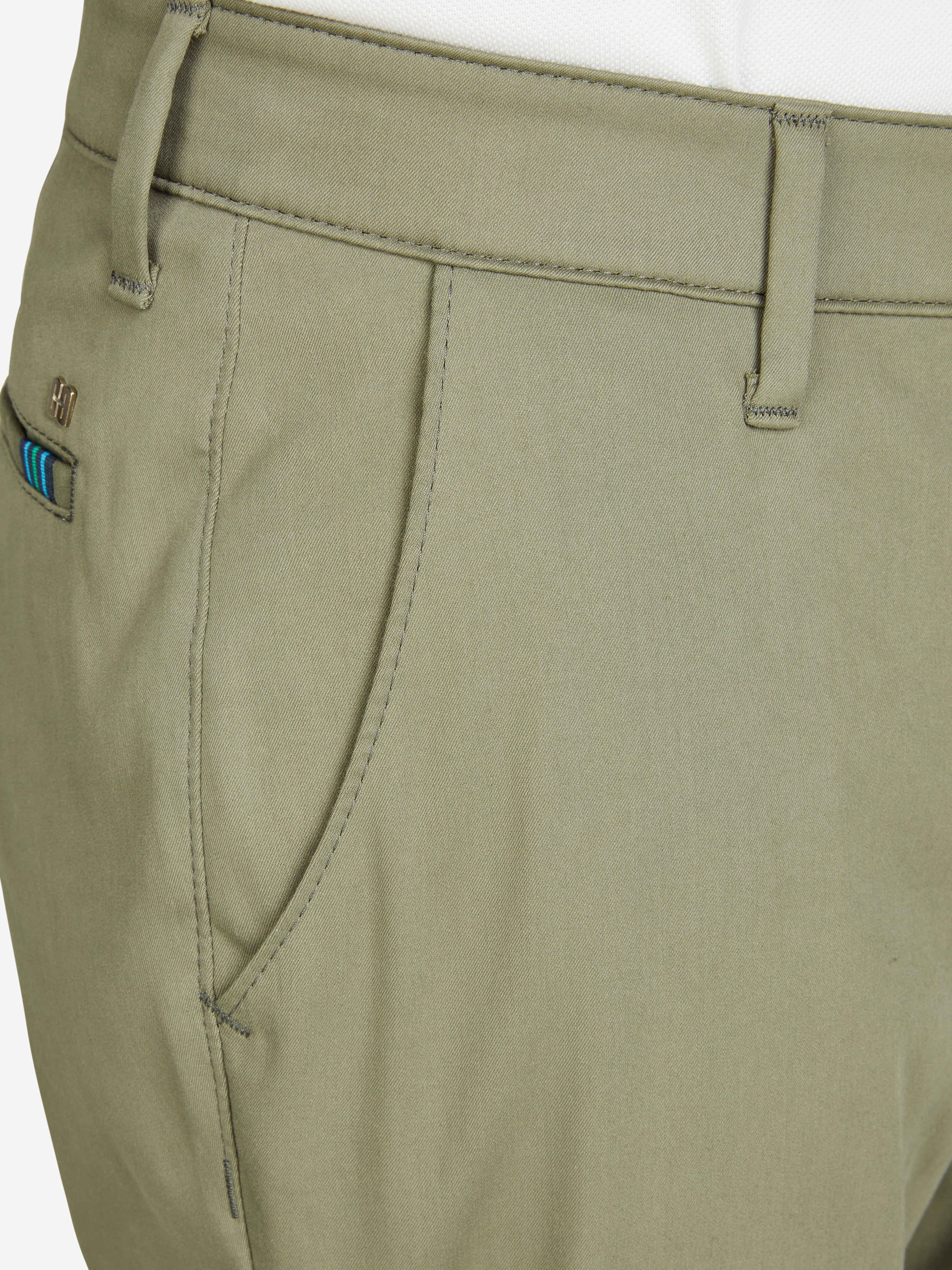 Nahaufnahme einer khakifarbenen Chino-Hose von Club of Comfort im Tapered Fit mit elastischem Comfortbund, Hemdenstopper und High Stretch Techno-Cotton. Die Hose hat eine normale Leibhöhe, mehr Platz im Gesäß und Oberschenkel, einen schmalen Beinverlauf und einen cleanen Look.
