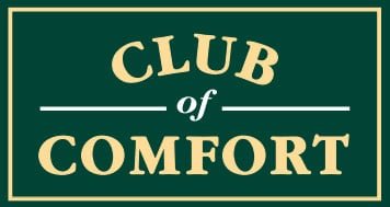 Ein grünes Logo mit weißer Umrandung und weißen Schriftzügen, die den Text "Club of Comfort" in Großbuchstaben zeigen; der Schriftzug ist in einer eleganten, klassischen Schriftart gestaltet.