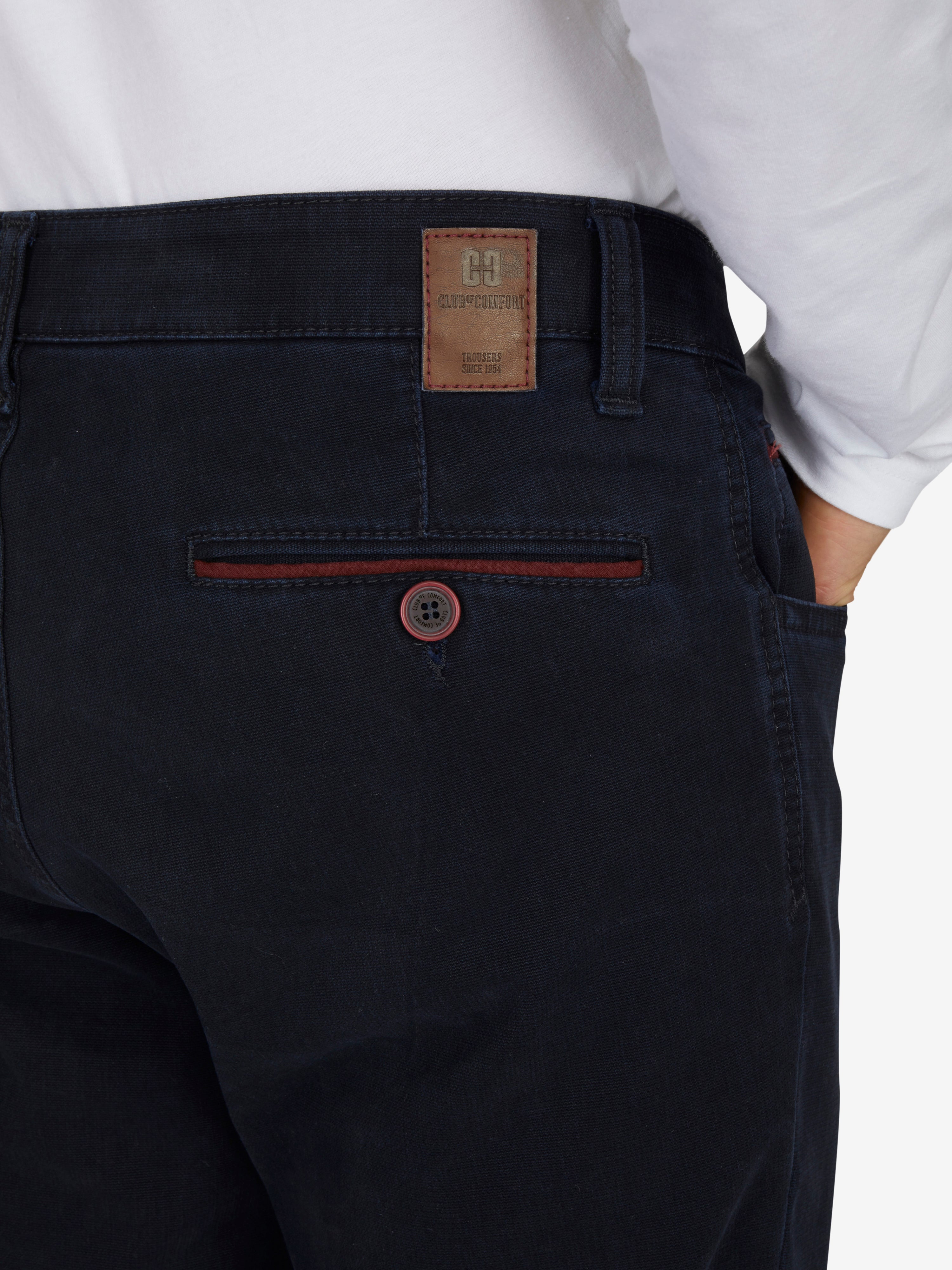 Herren-Hose MARVIN 7218 in Marine, aus Baumwolle mit High Stretch, modifizierte 5-Pocket-Style, Komfortbund, Hemdenstopper, schmaler Fußweite, Herbst/Winter, reflektiert den winterlichen Charakter durch Double Dye-Färbung, reguläre Leibhöhe, getragen, mit braunem Label und rotem Detail.