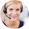 Nahaufnahme einer jungen Frau mit blonden Haaren, die freundlich lächelt und einen schwarzen Headset mit Mikrofon trägt, während sie sich offensichtlich in einem Kundenservice- oder Support-Umfeld befindet.