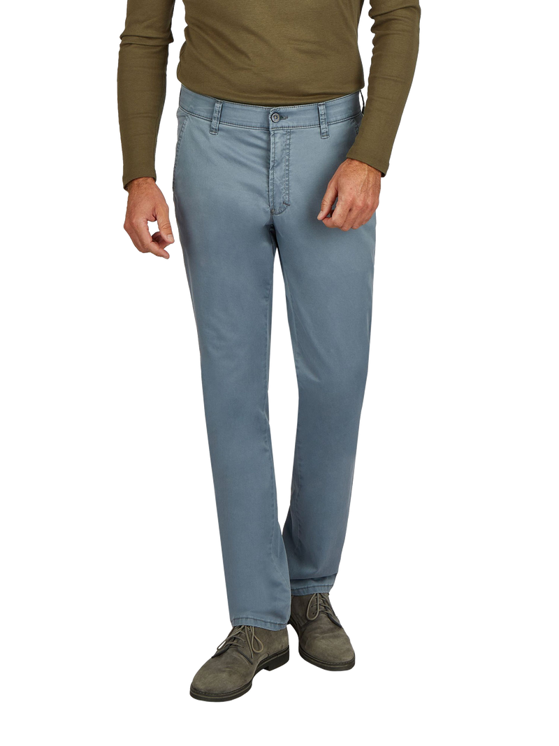 Blick auf eine Person im unteren Brustbereich, die eine hellblaue Jeans trägt, eine grüne Langarmjacke oder Pullover und graue Schuhe.